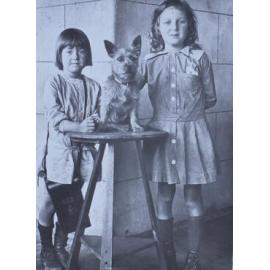 Two young girls standing with a pet dog