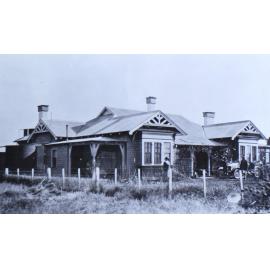 Unidentified house with some people and a car in front
