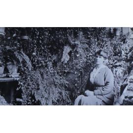 Unidentified woman sitting in a fernery