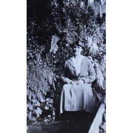 Unidentified woman sitting in a fernery