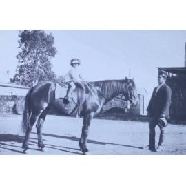 Young girl on a horse with a man watching on