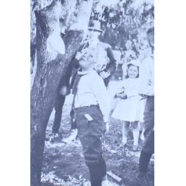 Young boy trying to eat an apple on a string