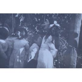 Four young children trying to eat apples on string