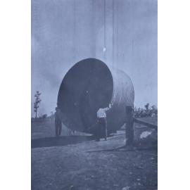 Two men moving a water tank