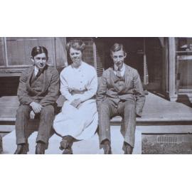 Two young men and a woman sitting on verandah steps