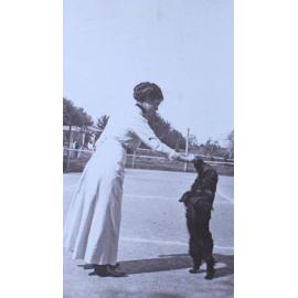 Unidentified woman with pet spaniel in the tennis court