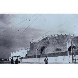 People walking past buildings at the side of a road