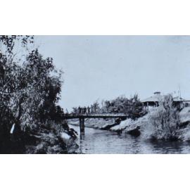 Soldiers on a footbridge over a creek