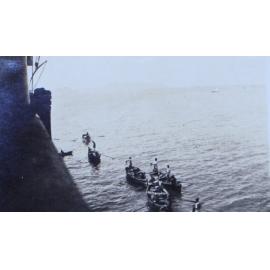 Row boats alongside a troop ship