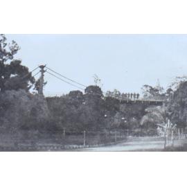 Soldiers on a footbridge looking over a park area