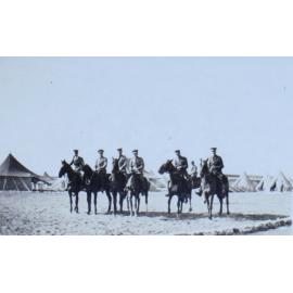 Group of mounted officers with tents in the background