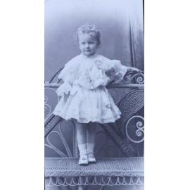 Young girl standing on a cane chair
