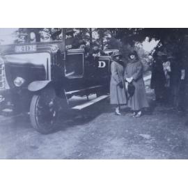 Two women standing near an open motor coach