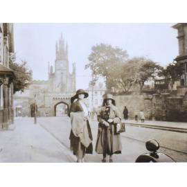 Two women standing on the street in front of a large gateway