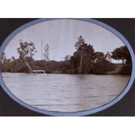 Small boat on a river with a house on the far bank