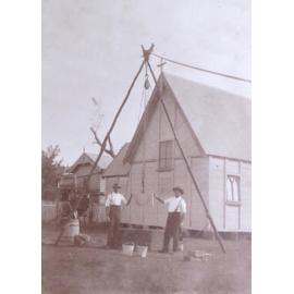 Two men setting a foundation stone in place for a small church