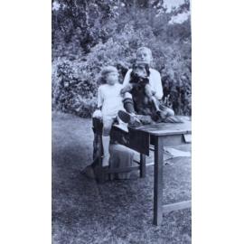 Boy and a girl sitting on a table with a pet dog