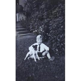 Young boy sitiing on the grass with a pet dog