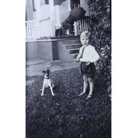 Young boy standing on the grass with a pet dog