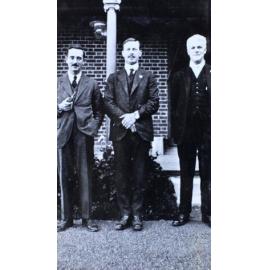 Three men standing in front of a house