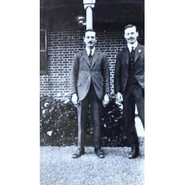 Two men standing in front of a house