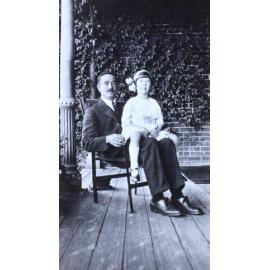 Man sitting on the verandah with a girl sitting on his lap