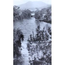 Looking down a flooded river to a bridge