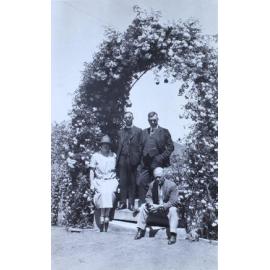 Three unidentified man and a woman under a garden arch