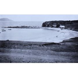 View of a small beach, boats in the water and the ocean beyond