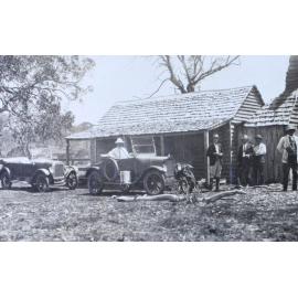 Group of men standing outside a bush hut