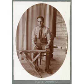 Seated man with knife at work bench