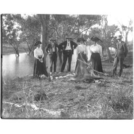Picnic party beside a river with campfire
