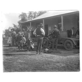 Group standing beside a motorcar