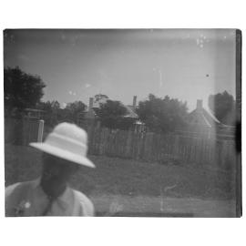 A man in a hat standing in front of a fenceline