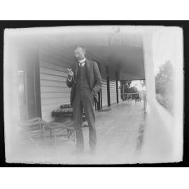 [D.M. Cameron] on a verandah looking at his pocket watch