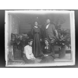 Three women and a man on a verandah with potted plants, 1904