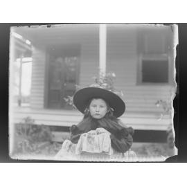 Girl wearing a hat in front of a house