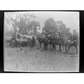 Seven men on horseback near a tent in a clearing