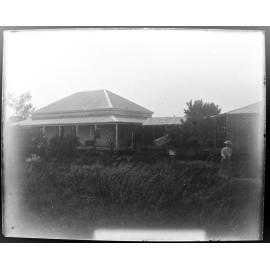 View of a house and sheds with a woman in the foreground