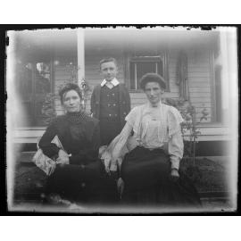 Two women and a boy in front of a house