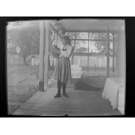 Woman on verandah holding a possum in a bucket