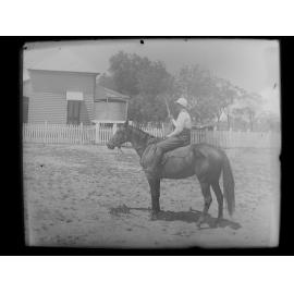 Boy on horse-back, holding a rifle