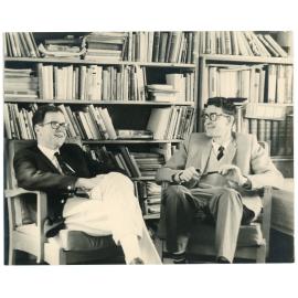 John Ryan and another gentleman seated in front of bookshelves