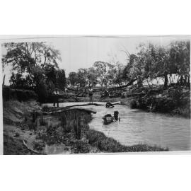 Young boys swimming in the creek with tin canoe