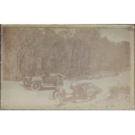 Car and utility stopped on mountain road, wheel change