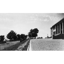 Armidale Teachers' College: View of gravelled area and garden in front of main building (on left), looking east, 1930