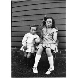 Two unidentified children sitting on a wicker chair probably at 63 Barney Street, Armidale