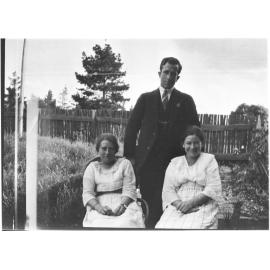 Unidentified man [with RSL pin] standing behind two women