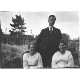 Unidentified man [with RSL badge] standing behind two women