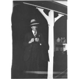Unidentified man [with RSL pin] standing on the verandah of 63 Barney Street, Armidale